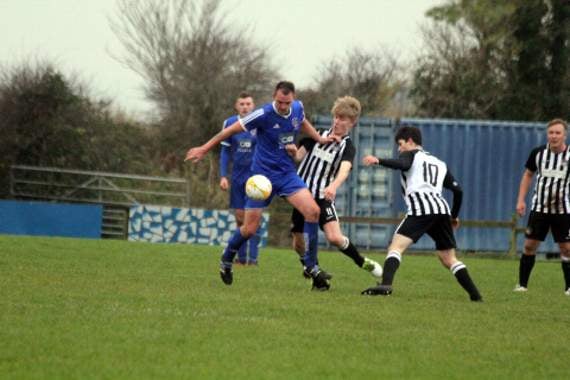 Bude Town’s Dan Starkey (blue) looks to shrug off the attention of two Penzance players during Saturday’s clash at Broadclose Park. Picture: Paul Hamlyn