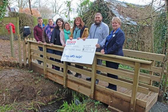 Shelley Vanstone from Tesco is pictured presenting a cheque for £4,000 to Lifton CP on their new bridge connecting the school to its pond area. Pictured from left: Pete Bluett, Abi Bluett, Leanne Barriball, Victoria Kinger (foundation leader), Melanie Cripps (head teacher), Shelley Vanstone and Mike (Tesco).