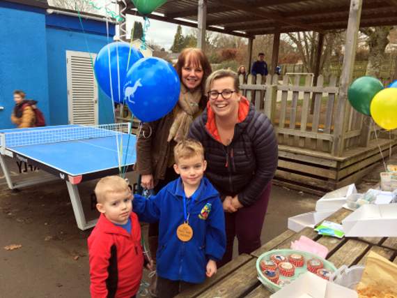Freddie Bluett (centre) is pictured with his mother Abi, headteacher Melanie Cripps, and little brother at his cake sale on Friday, January 24. Picture: Post