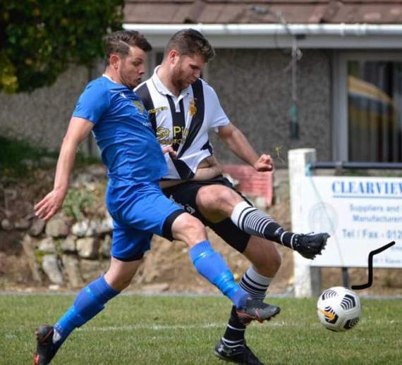 Bude's star striker Billy Hopcroft (blue) will hope to score the goals that fire the Seasiders back to Step Six.