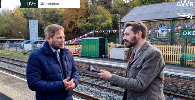 TV presenter Tim Dunn interviewing Transport Minister Grant Shapps on Okehampton station platform.