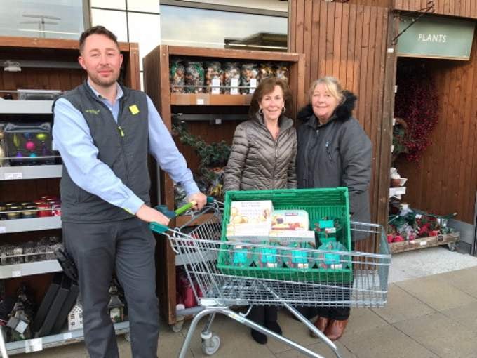 Luncheon Club organisers Eileen Steele and the new cook Julie Parsons are pictured collecting Christmas puddings and cream from Waitrose & Partners’ Holsworthy store team leader James Dennis