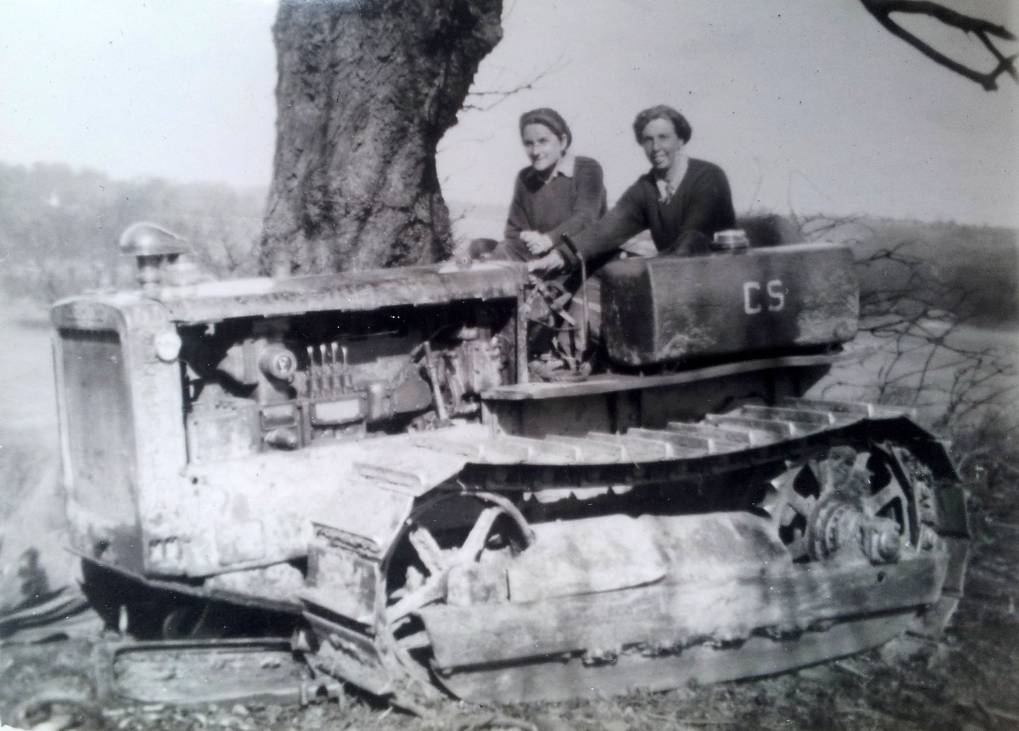 Joyce Elizabeth Gaster (left) driving a caterpillar tractor at Alice Holt Forest and, below, with corps members