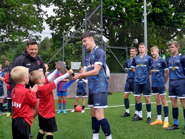 Under-16s captain Charlie Wills is presented with the National Shield by some younger players.