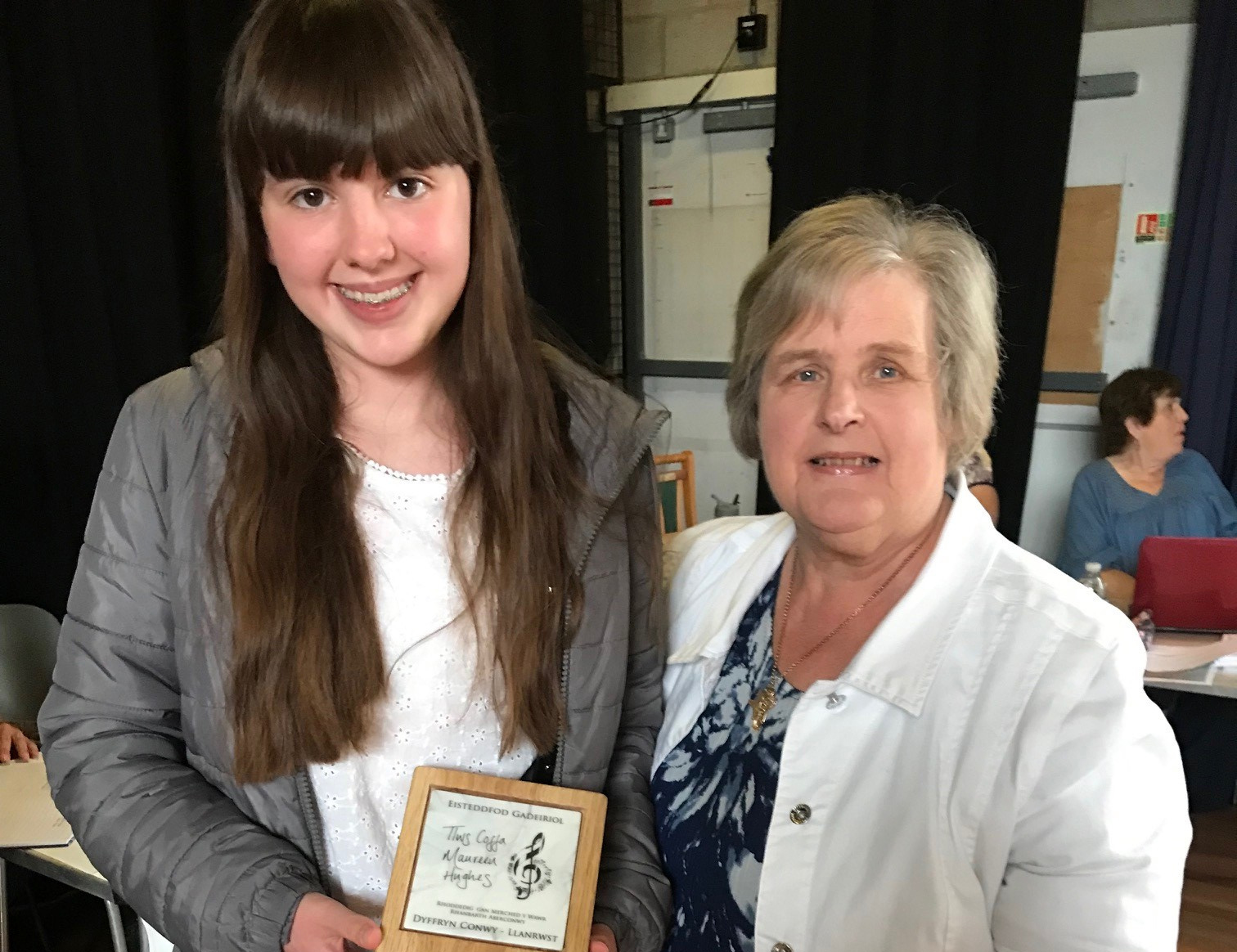 Alma Dauncey Roberts presenting the Tlws Maureen Hughes to Lea Mererid Roberts of Pwllheli