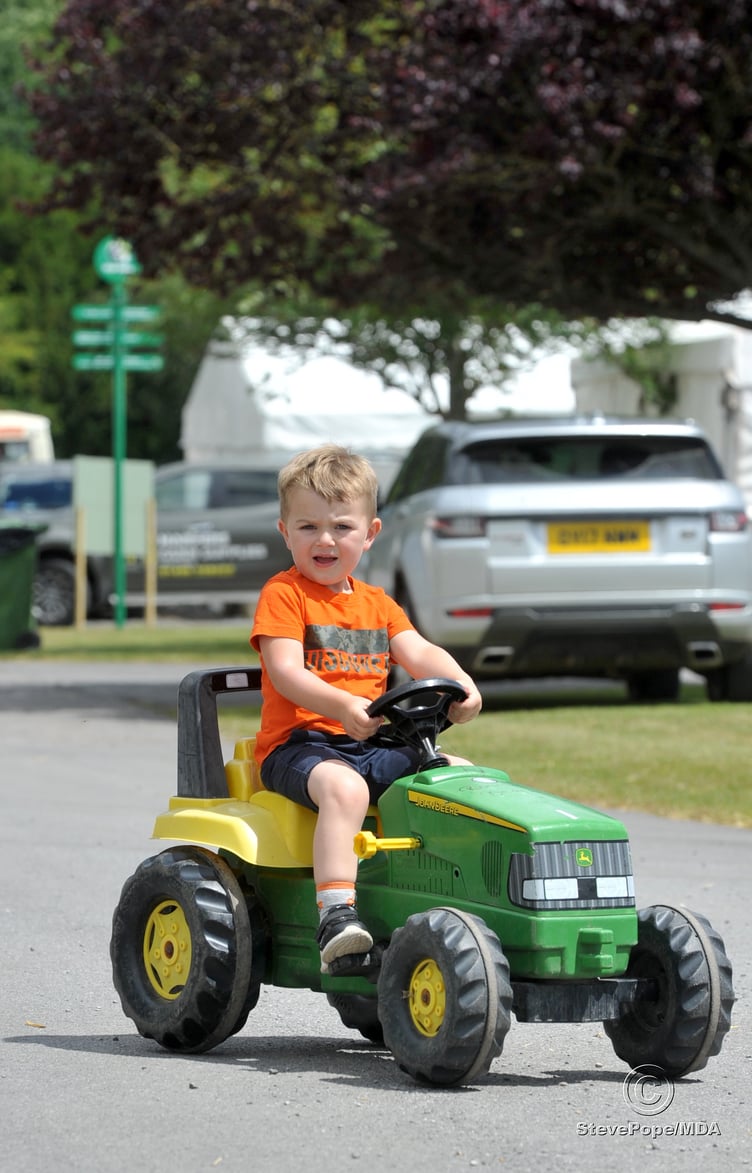 Tractors of all sizes on the showground and three year old Ronnie Beach from Hillside Farm at Ashcott in Somerset has one that's just his size to get about Westpoint