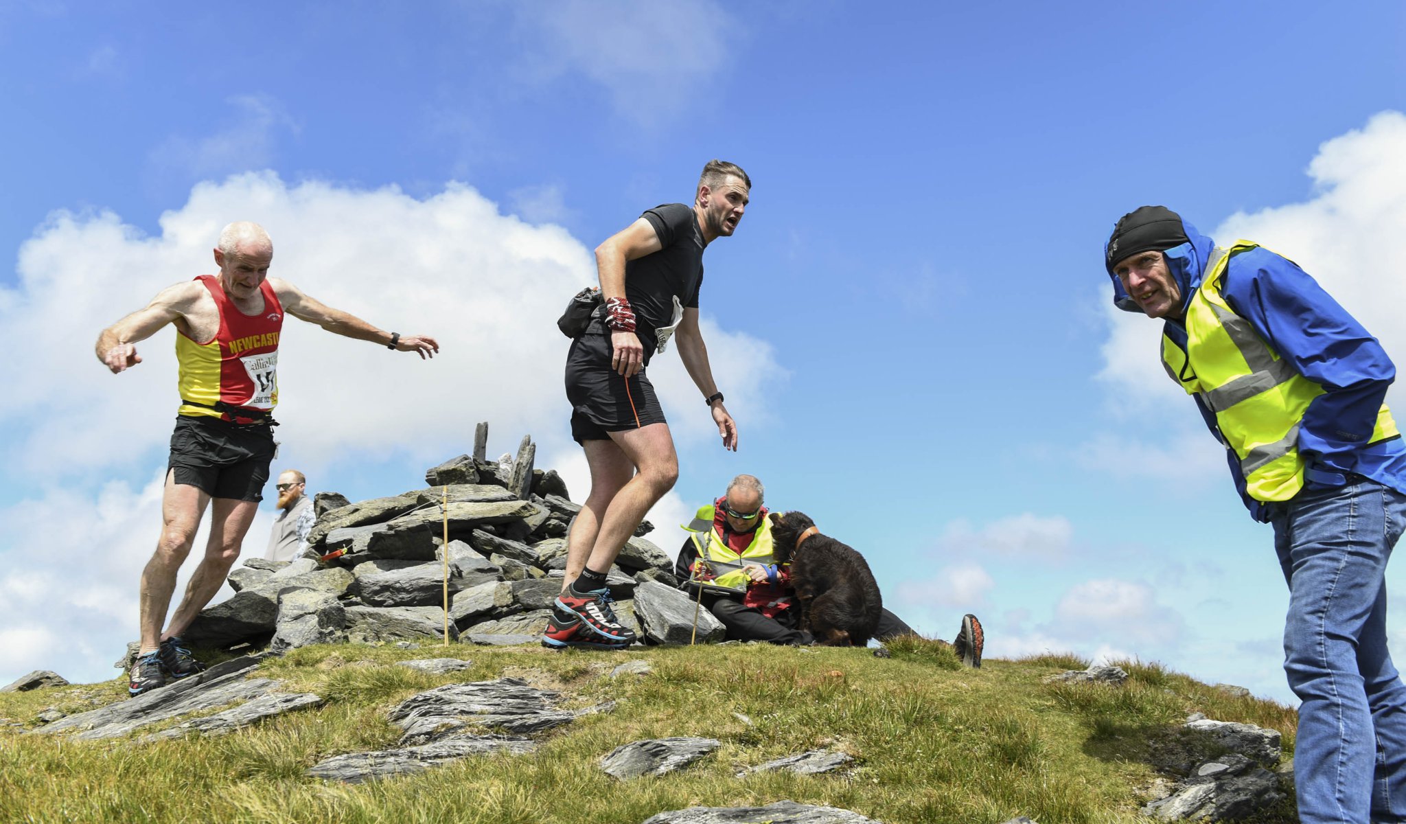 Dominic McGreevy Sr and Jr at the summit of Beinn y Phott together. Wearing his Newcastle, Co Down vest, Dominic won the over-60s class, while Dom Jr - the former Peel and St Mary’s footballer - was 1min 17sec behind at the close. Checking the numbers are Jim Macgregor, aided by his loyal search and rescue dog Ruby May, with Julian Corlett marshalling on the far right (Photo: Philip Crowe)