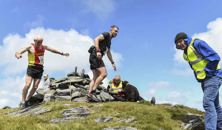 Dominic McGreevy Sr and Jr at the summit of Beinn y Phott together. Wearing his Newcastle, Co Down vest, Dominic won the over-60s class, while Dom Jr - the former Peel and St Mary’s footballer - was 1min 17sec behind at the close. Checking the numbers are Jim Macgregor, aided by his loyal search and rescue dog Ruby May, with Julian Corlett marshalling on the far right (Photo: Philip Crowe)