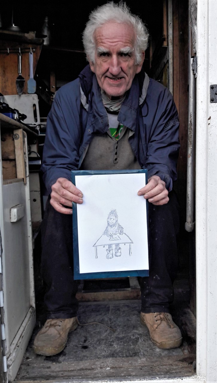 Mike holding his original Yeti-writer sketch in his converted-lorry home Porthmadog