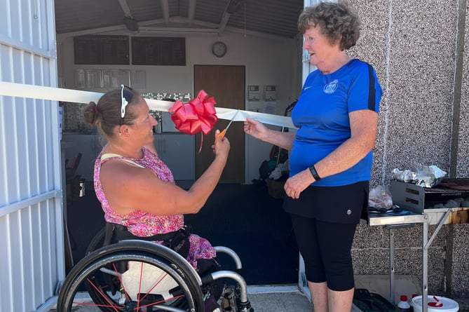 Paralympian Rachel Morris cuts the ribbon to open Badshot Lea Tennis Club’s floodlights and new accessible facilities chair, watched by club chair Gillian Hyman