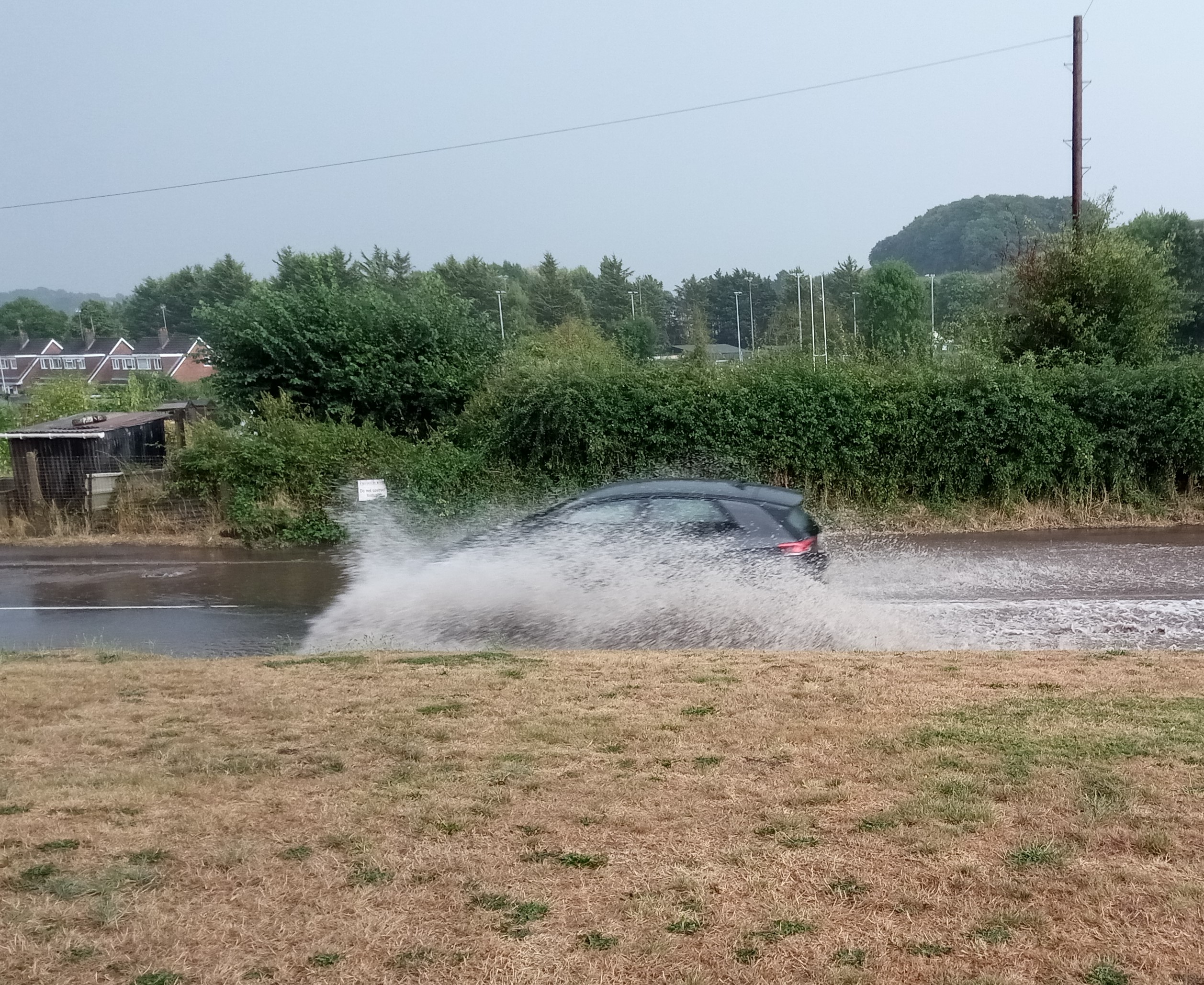 Vehicles travelling through the flooded Exhibition Road in Crediton.