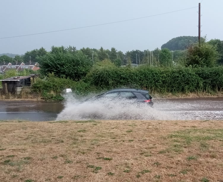 Vehicles travelling through the flooded Exhibition Road in Crediton.