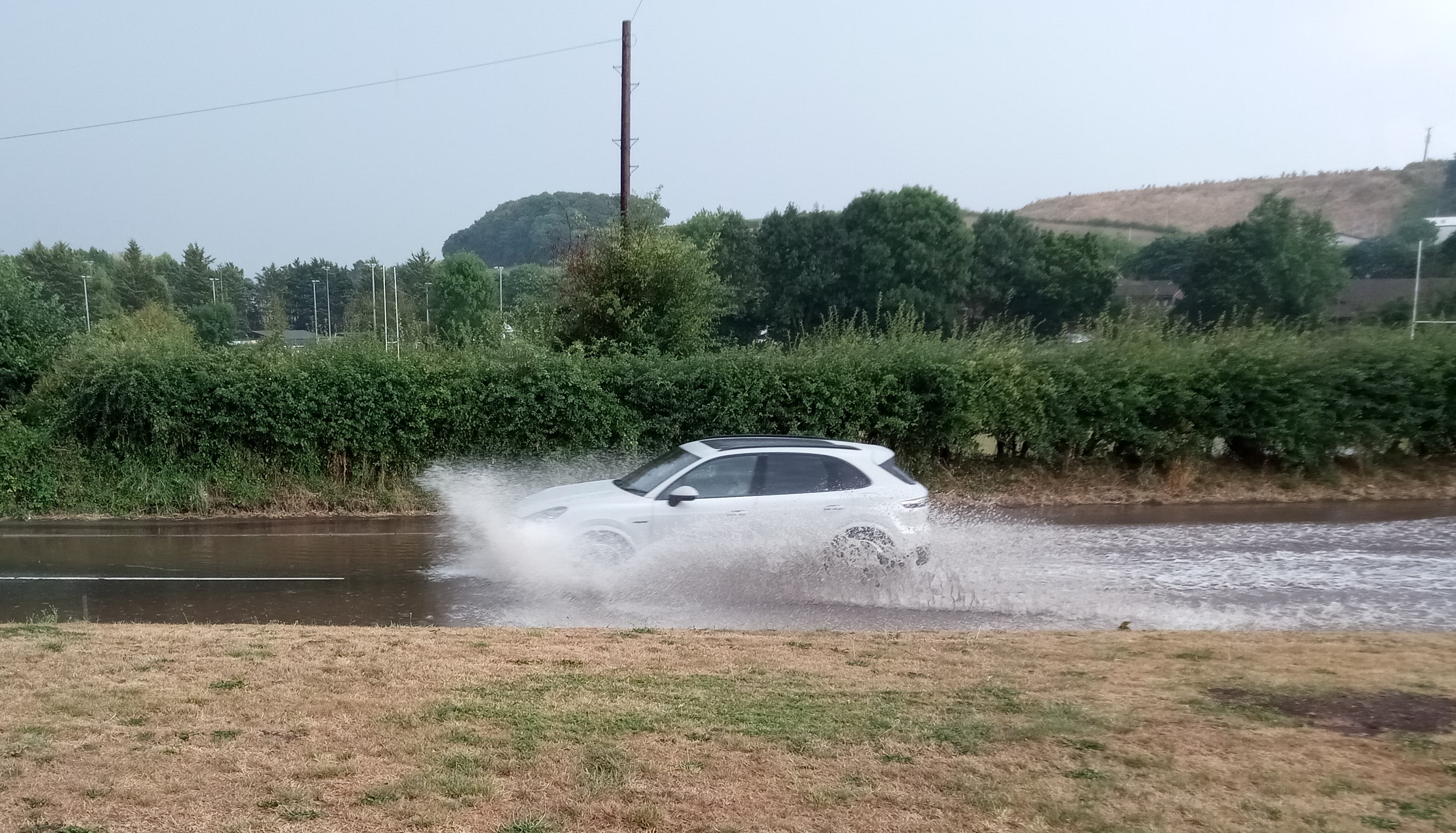 Vehicles travelling through the flooded Exhibition Road in Crediton.