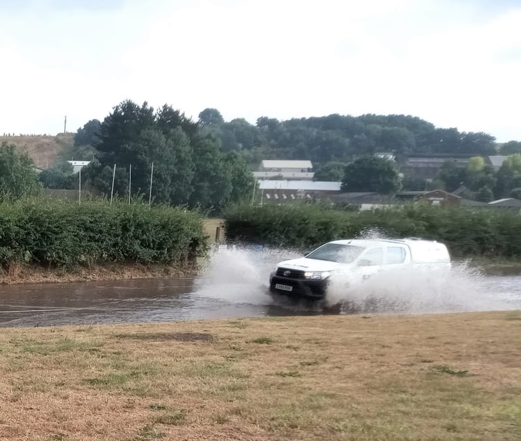 A vehicle travelling through the flooded Exhibition Road in Crediton.