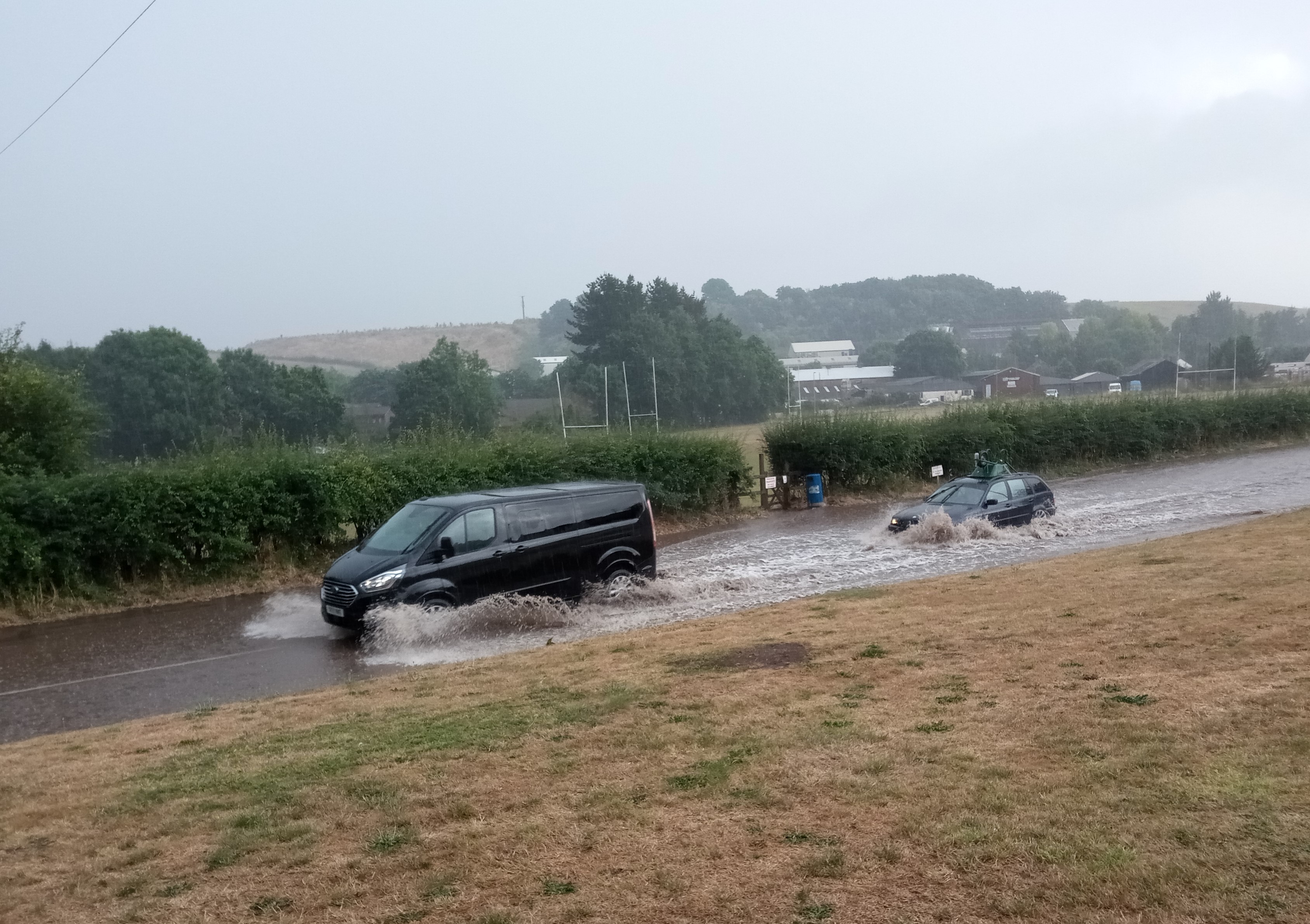 Vehicles travelling through the flooded Exhibition Road in Crediton.