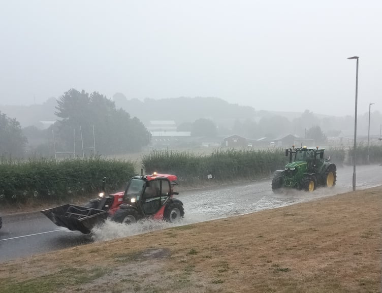 Tractors travelling through the flooded Exhibition Road in Crediton.