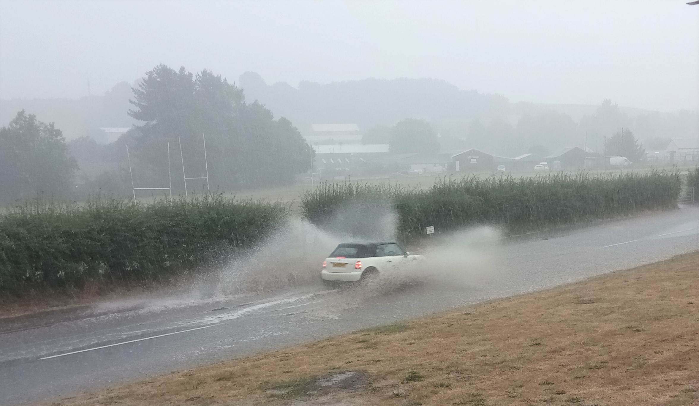 A vehicle travelling through the flooded Exhibition Road in Crediton.