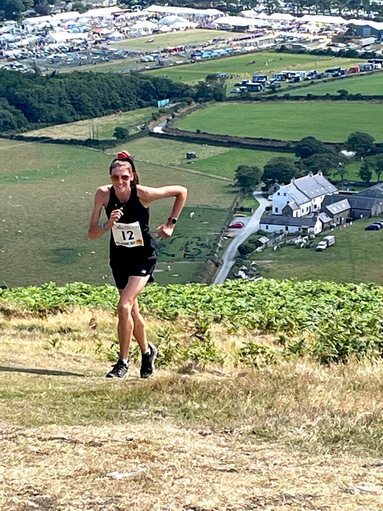 Women’s winner Hannah Moore traverses Peel Hill with the Royal Manx Show in the background. She finished in a time of 20 minutes 32 seconds (Photo: Gary Sherry)