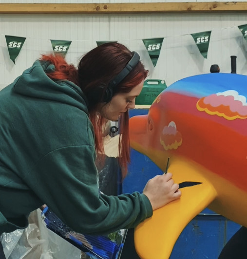 Lorna Smith paints a gull on to her Peel Sunset dolphin