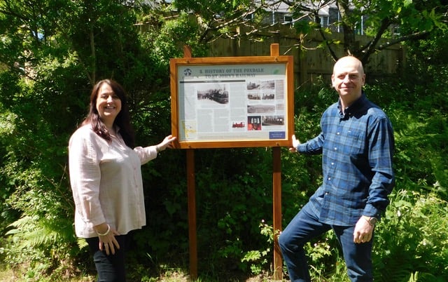 Roz and Richard Melia, sponsors of the interpretation board project in Foxdale next to board three, showing the history of the St John's to Foxdale railway