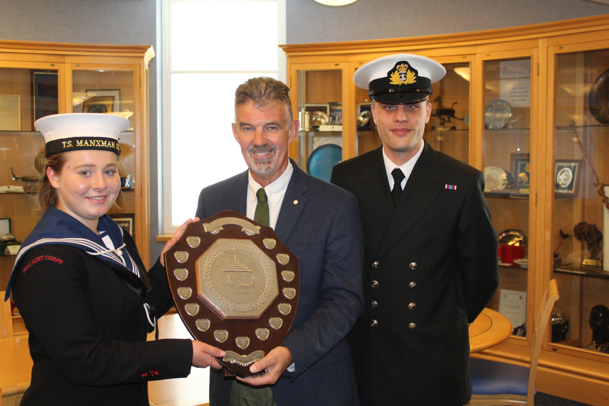 Orla Goddard collects the Best Turned Out individual award from President of Tynwald Laurence Skelly MLC, alongside sub-lieutenant Jamie Ward