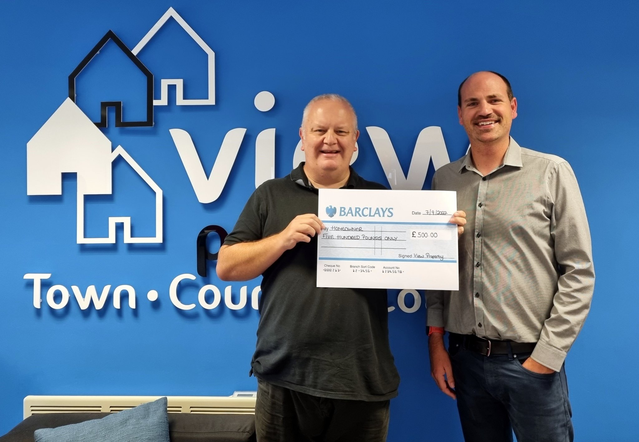 Mr and Mrs Pike receiving their cheque from Sophie at View Property