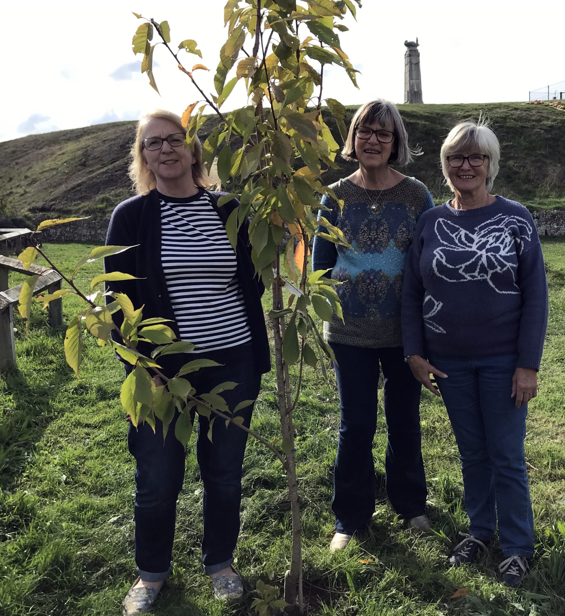 ABOVE: Gill Daniels, Dorothy Flaxman and Joan Trewin admire the WI flowering cherry tree; Below, Lynn Geldart receives a thank you gift from Carol Sparham