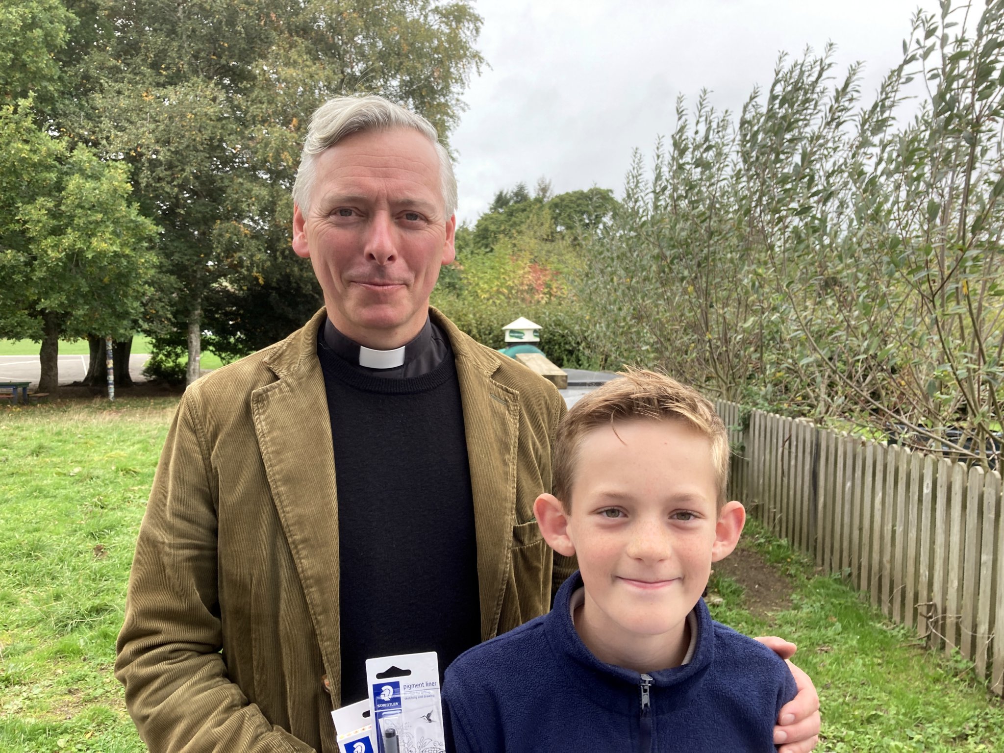 Logo design competition winner Max Horncastle being presented with his prize by the reverend Paul Seaton-Burn.