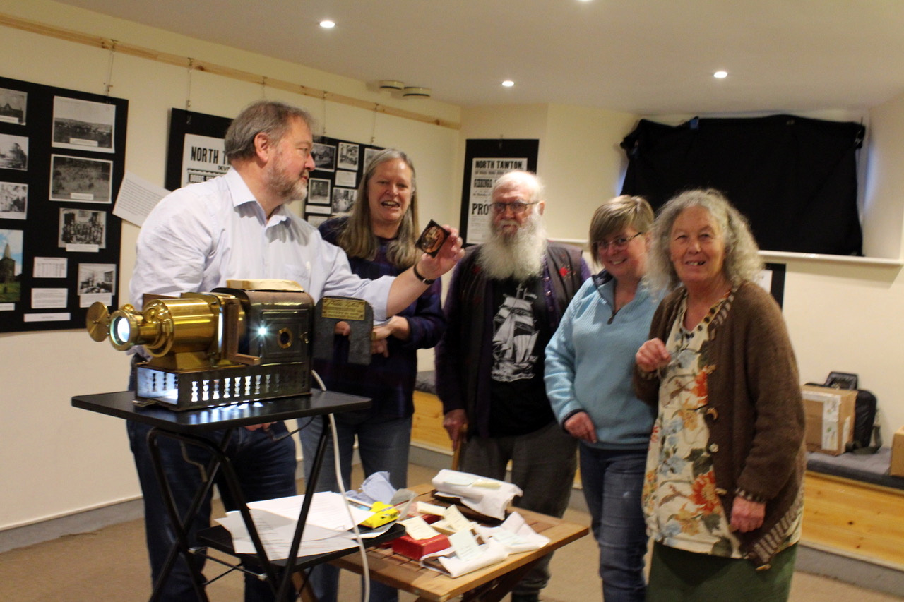 Left to right, Dr Richard Crangle of Exeter of the Magic Lantern Society showing a slide to Sheila Riley a member of the Events Committee, story teller Michael John Dacre, Dawn Barnsley-Dale main organiser and Wendy Dacre. SR 6455