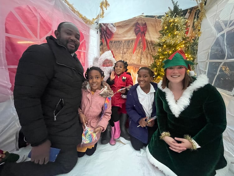 A family with Father Christmas and his Elf.