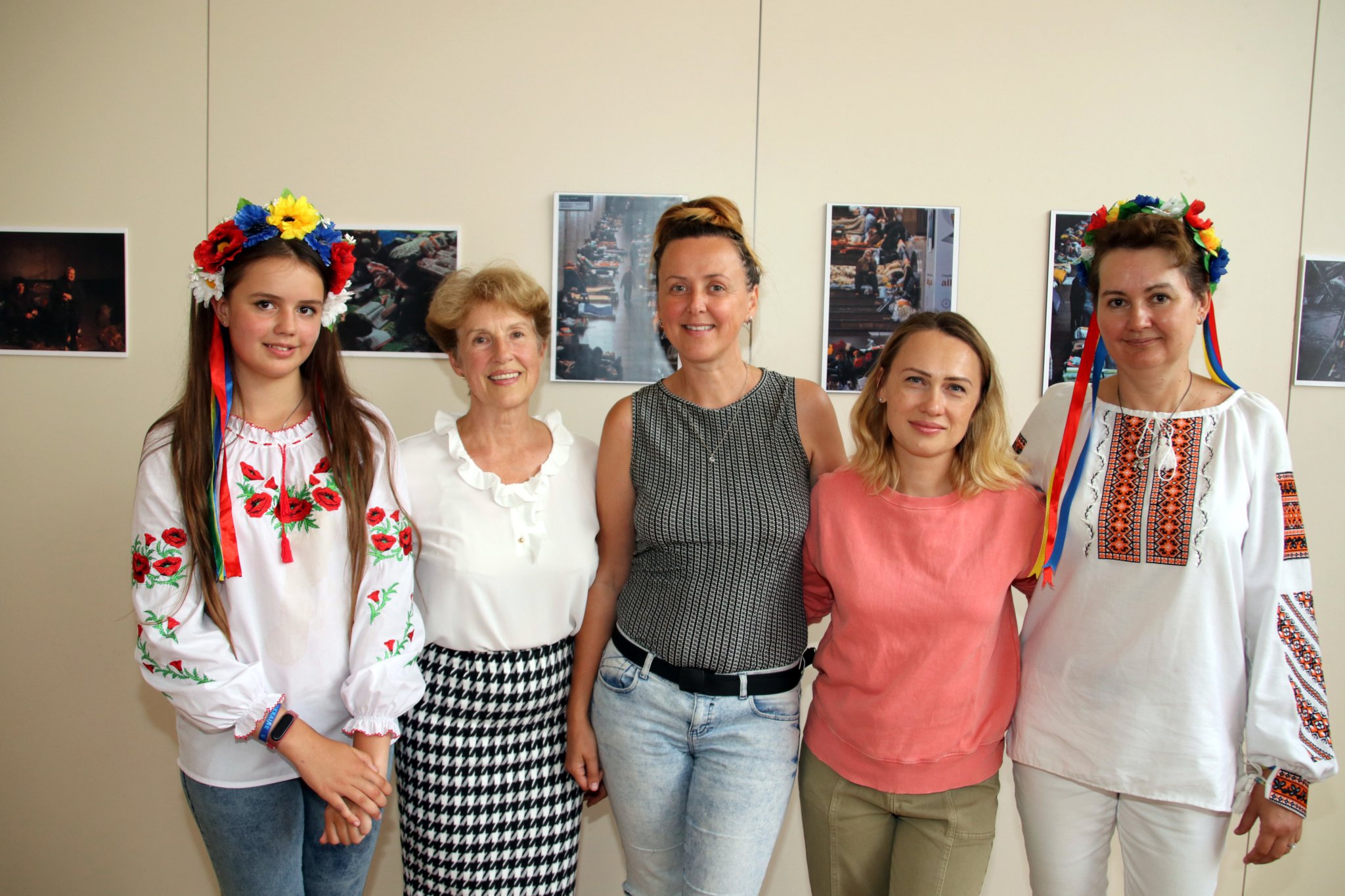 Some of the Crediton Ukrainian refugees and exhibition co-ordination Cllr Natalia Letch (second left), with some of the images of the Ukraine conflict. AQ 8454