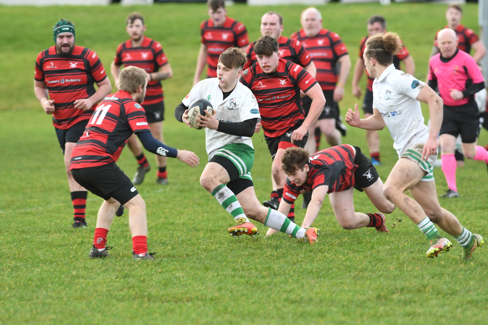 Nomads Whites’ pace men Tom Collister (with ball) and Tony Quinn isolate Ramsey wing Simon Corlett (red and black No.11) during Saturday’s Manx Shield encounter at Mooragh Park (Dave Kneale DK230107(10))