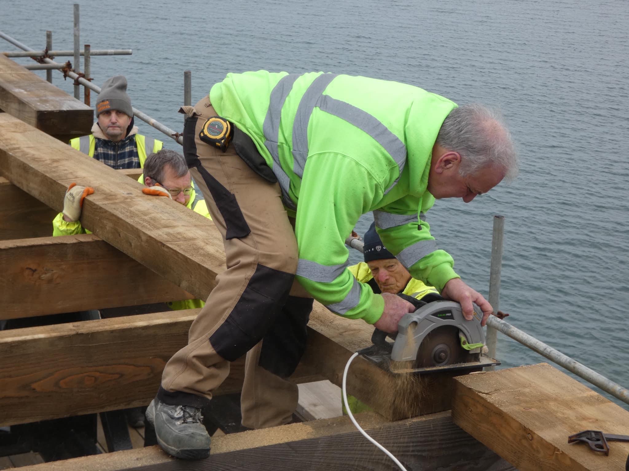 Queen's Pier: A wooden beam is cut to size