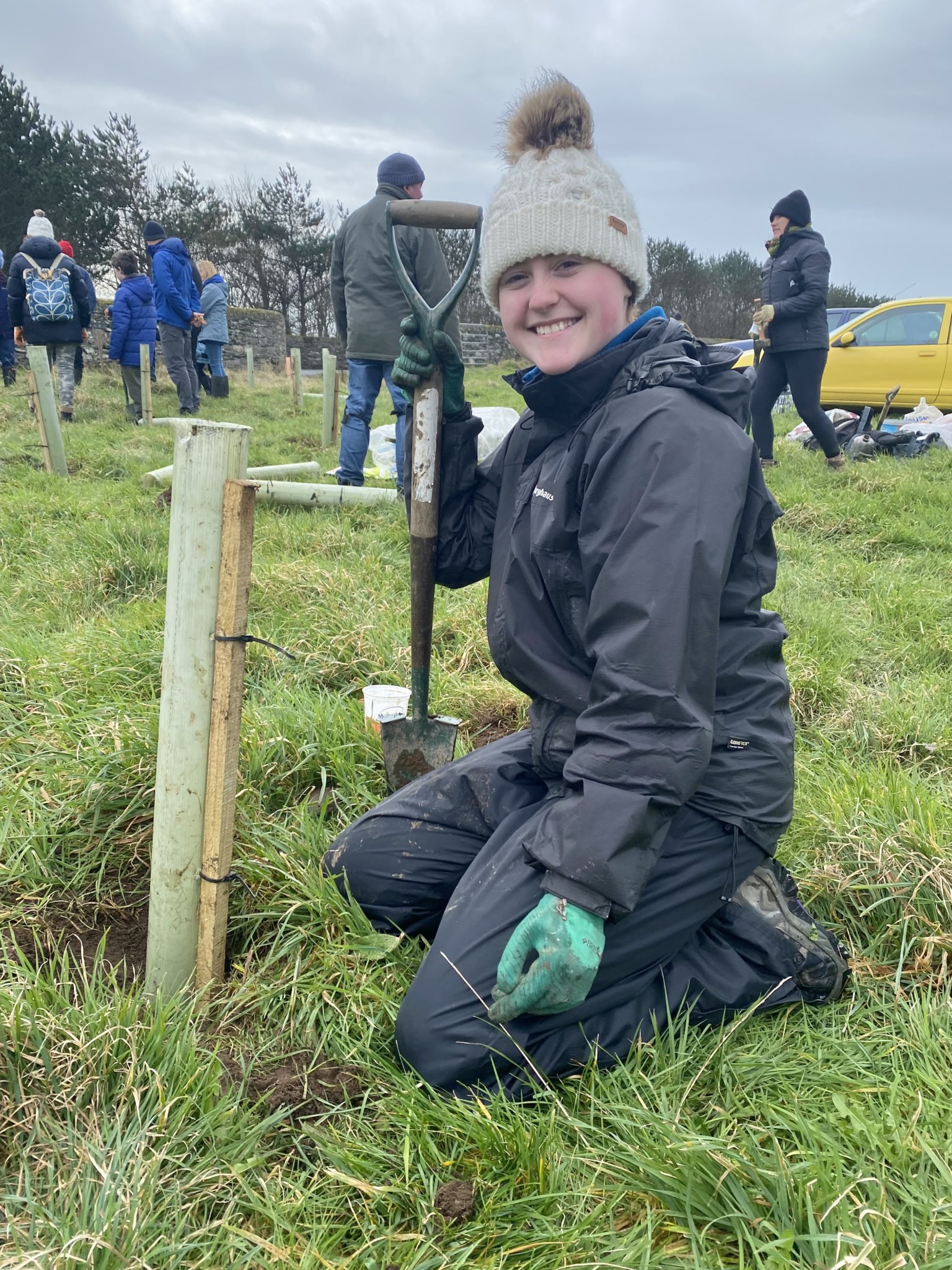 Bethany McGreevy next to a sapling she has planted