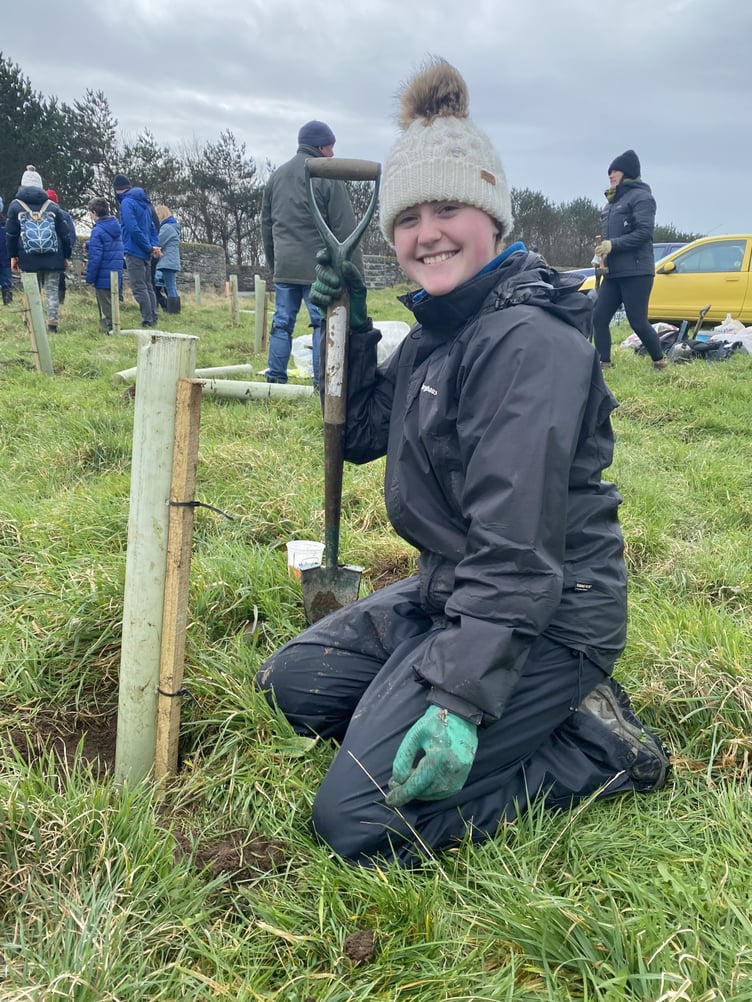 Bethany McGreevy next to a sapling she has planted