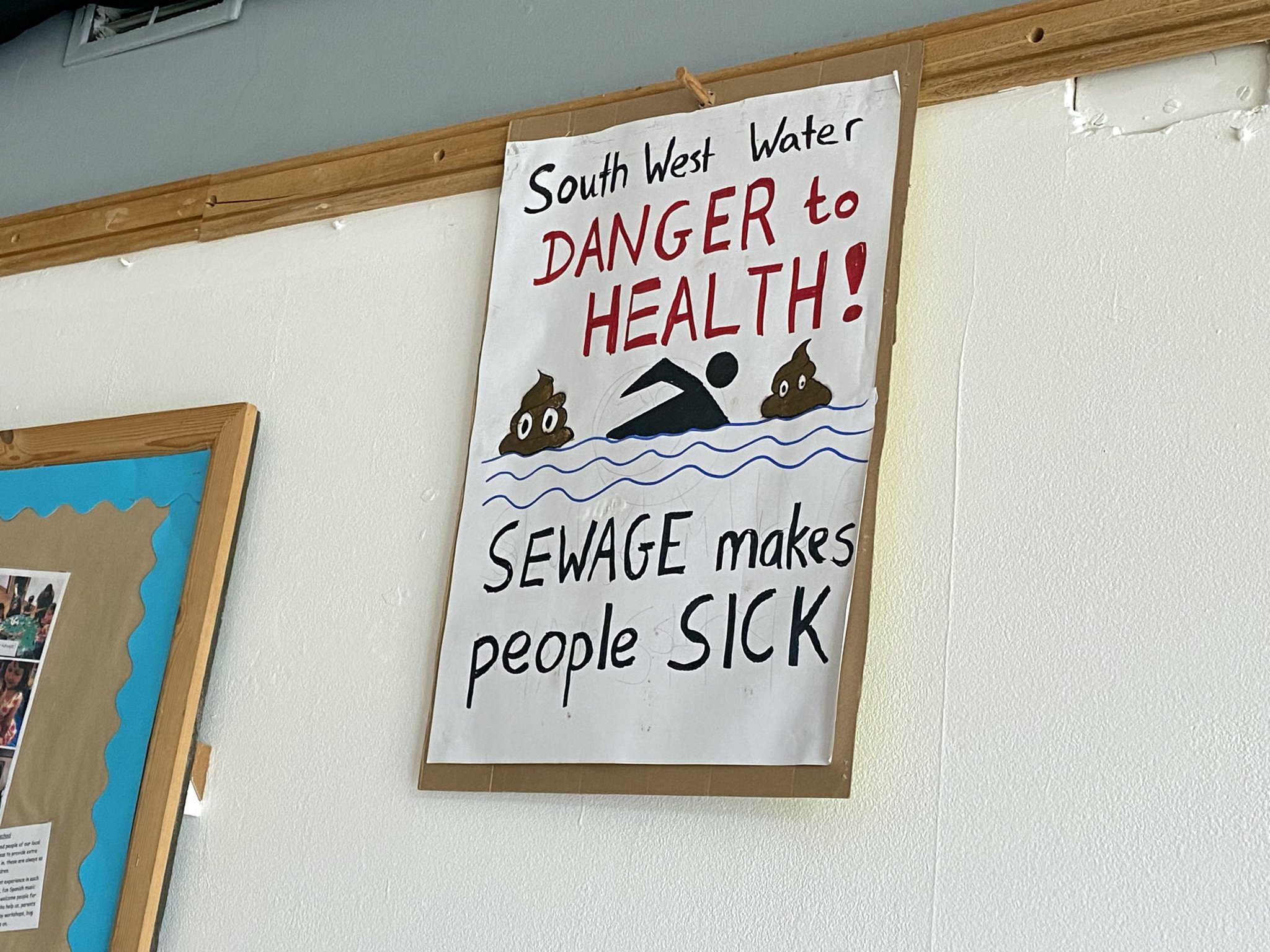 A sign inside of the village hall which reads "South West Water, danger to health, sewage makes people sick"