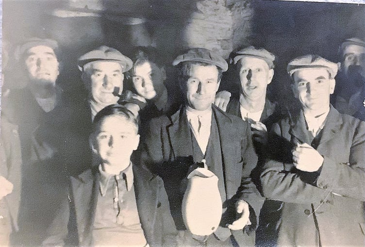 Cider making in the cider house at Eastern Farm in the 1940s. Holding the flagon is Tom “Tort” Taylor. In the foreground is Georgie, a young evacuee. Also pictured are (l-r) Steve Holt, Doc (?) Baker, Bill Lewis, Arthur Reynolds (?), Tom Amory, Mr Haste