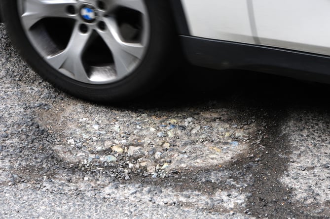 A car drives through one of the many potholes at the junction of Union Road and South Street in Farnham on Tuesday, April 25