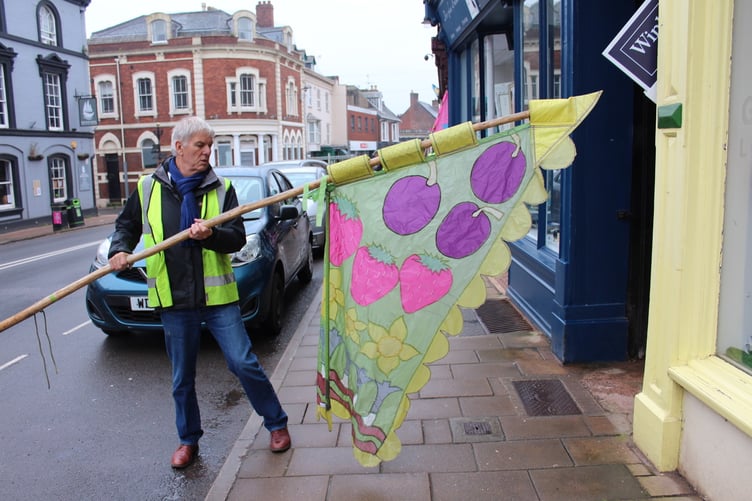 Rotarian Paul Butt with the flag for Four Seasons on the High Street. SR 7553