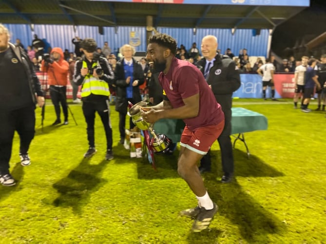 Farnham Town's Lamar Koroma lifts the Southern Combination Cup after Wednesday night's dramatic final victory