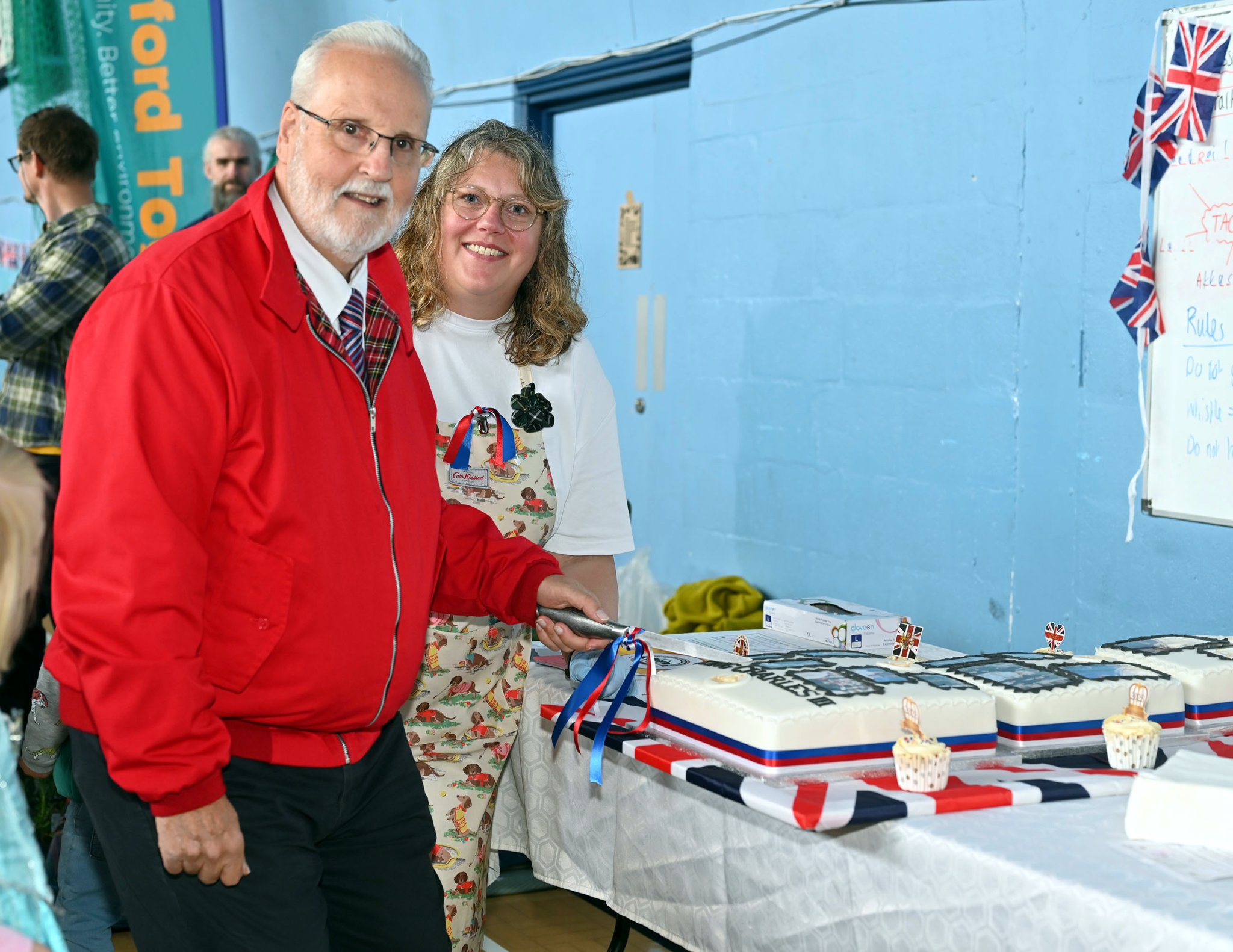 Robert Rothchell (Camelford Town Mayor) as the honoiur of cutting the Coronation Cake lookling on is Kirsty Ferguson who made the delcious cake