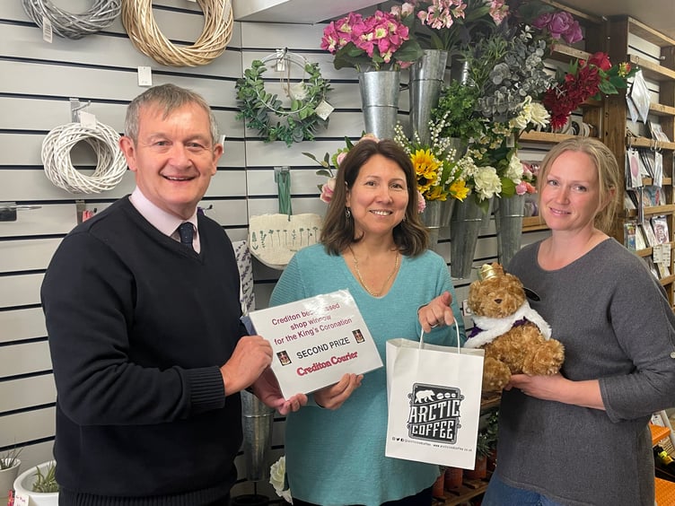 Alan Quick, Editor, ‘Crediton Courier’, presents Lilian Cozens, proprietor, Divine Flowers, with a voucher and goodies from Crediton Dairy with Joanne Tripp, right, holding the second prize certificate. AQ 8889