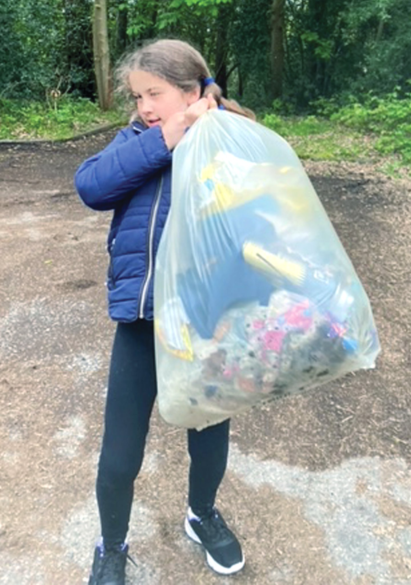 CLEANING UP – Juliet Tudoran collecting litter and toting the sack she filled with rubbish.