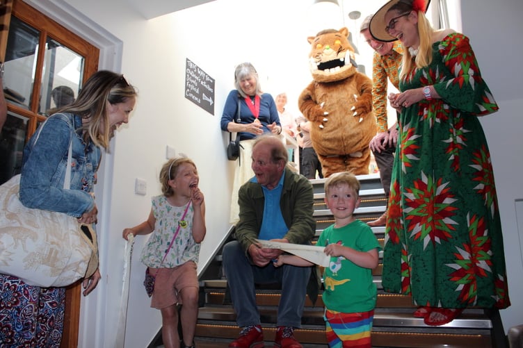 The ribbon across the stairs to the extension has been cut by three years-old Quinton Cook, helped by eight years-old Cora Whitehouse with Michael Morpurgo and behind, Crediton Mayor Cllr Elizabeth Brookes-Hocking, the Gruffalo, Philip Reeve and Sarah McIntyre on the steps leading up to the extension. SR 8093
