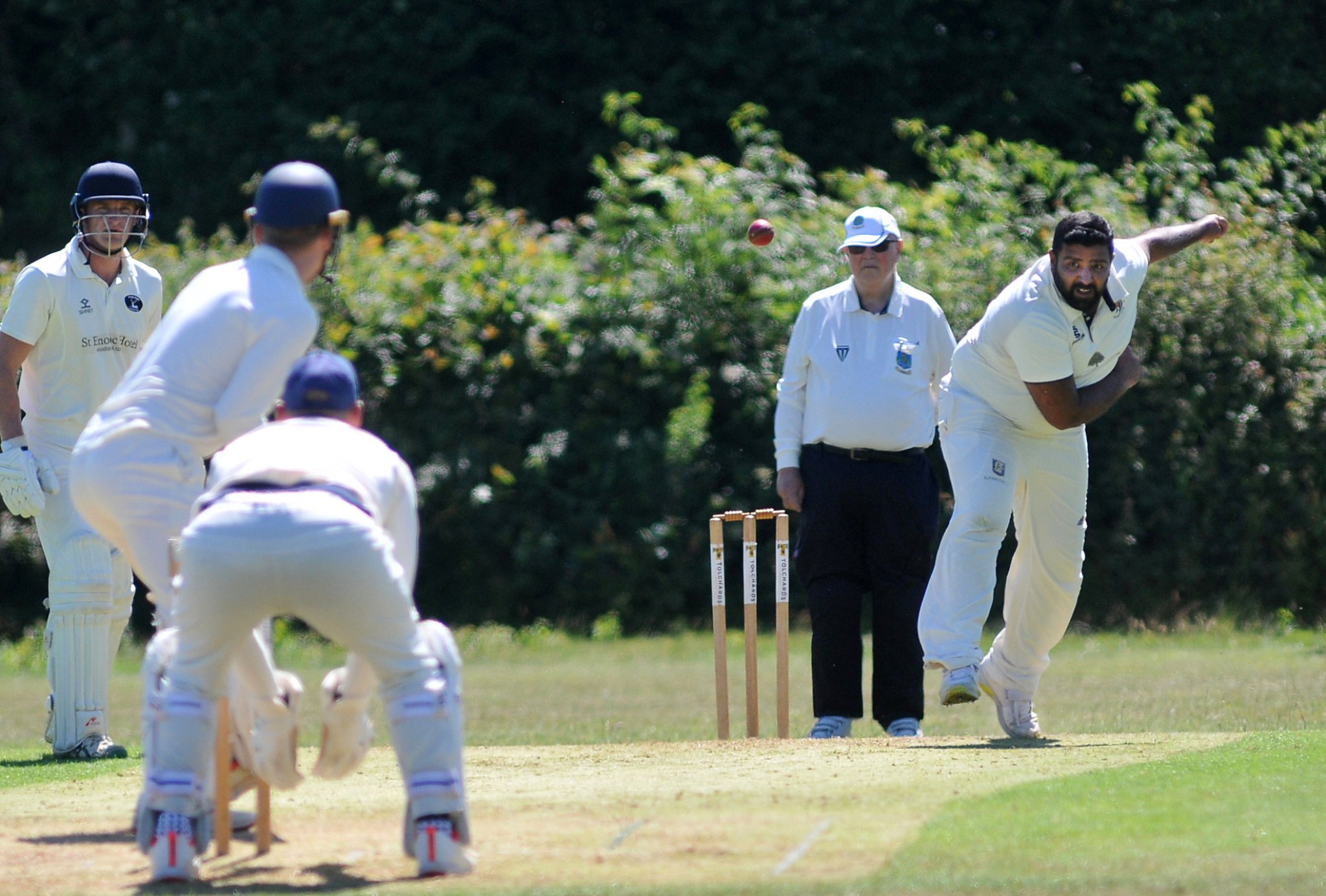 MAIN: Chudleigh’s Kam Singh bowling. CIRCLE: Harrison May collects the ball belted skyward by Bridestowe’s skipper Daniel Forgarty off Kim Singh’s bowling. Pictures by Steve Pope/Mid-Devon Advertiser.