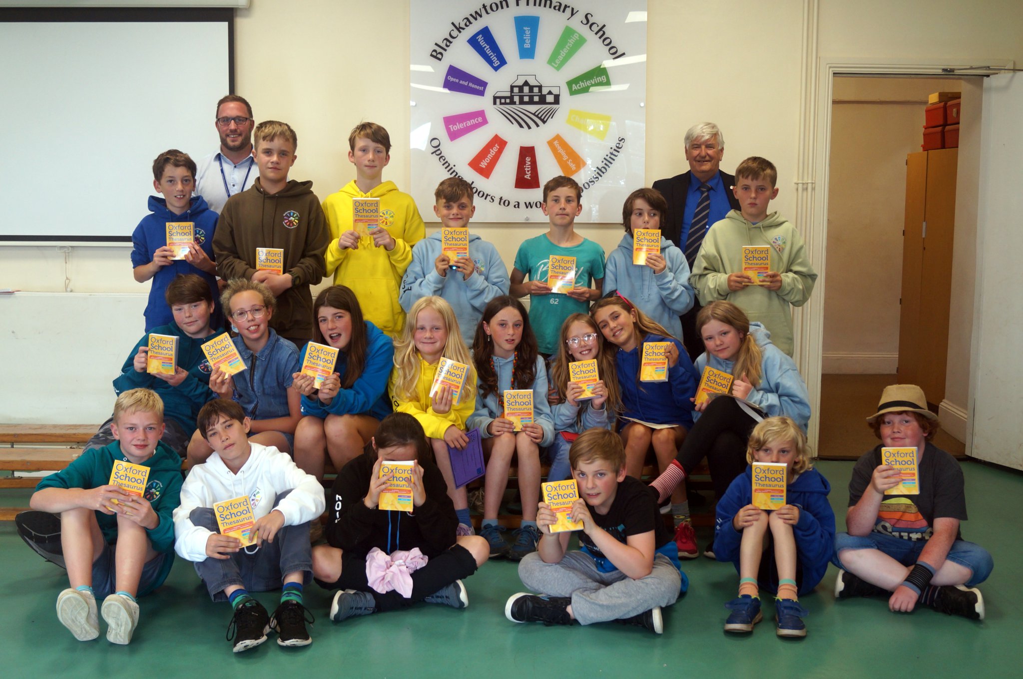 2. Blackawton Primary School children and their books with Rotarian Hilary Bastone (right) and headteacher Liam Fielding (left).