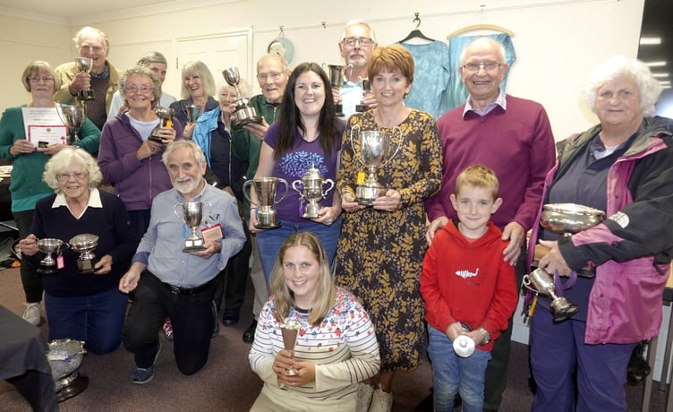 Above, the show’s cup winners; right, Veronica Barden with her winning entry in the Top Vase category; below, Kate and Trevor Jeans, who won their rose and sweet pea classes, with some of their exhibits; left, Mike King with his trophies for best vegetable exhibit and best shallots; top left, chair of Bere Ferrers Parish Council Cllr Peter Crozier presenting Margaret Wildman with her RHS Banksian Medal for the most points in the horticultural classes. Pictures by Ann Parsons.