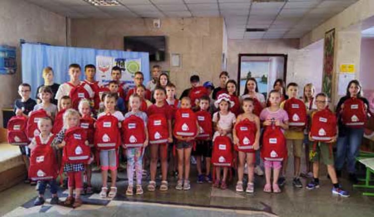 Young Ukrainian pupils show off their School In A Bag rucksacks, September 2023.