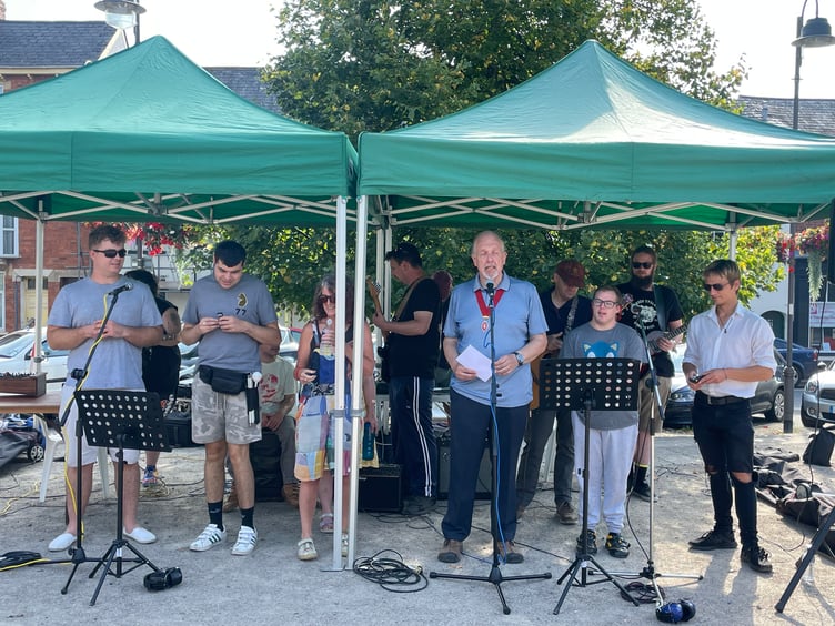 The Deputy Mayor of Crediton, Cllr Steve Huxtable opening the event with The Turning Tides musicians and singers. AQ 6449