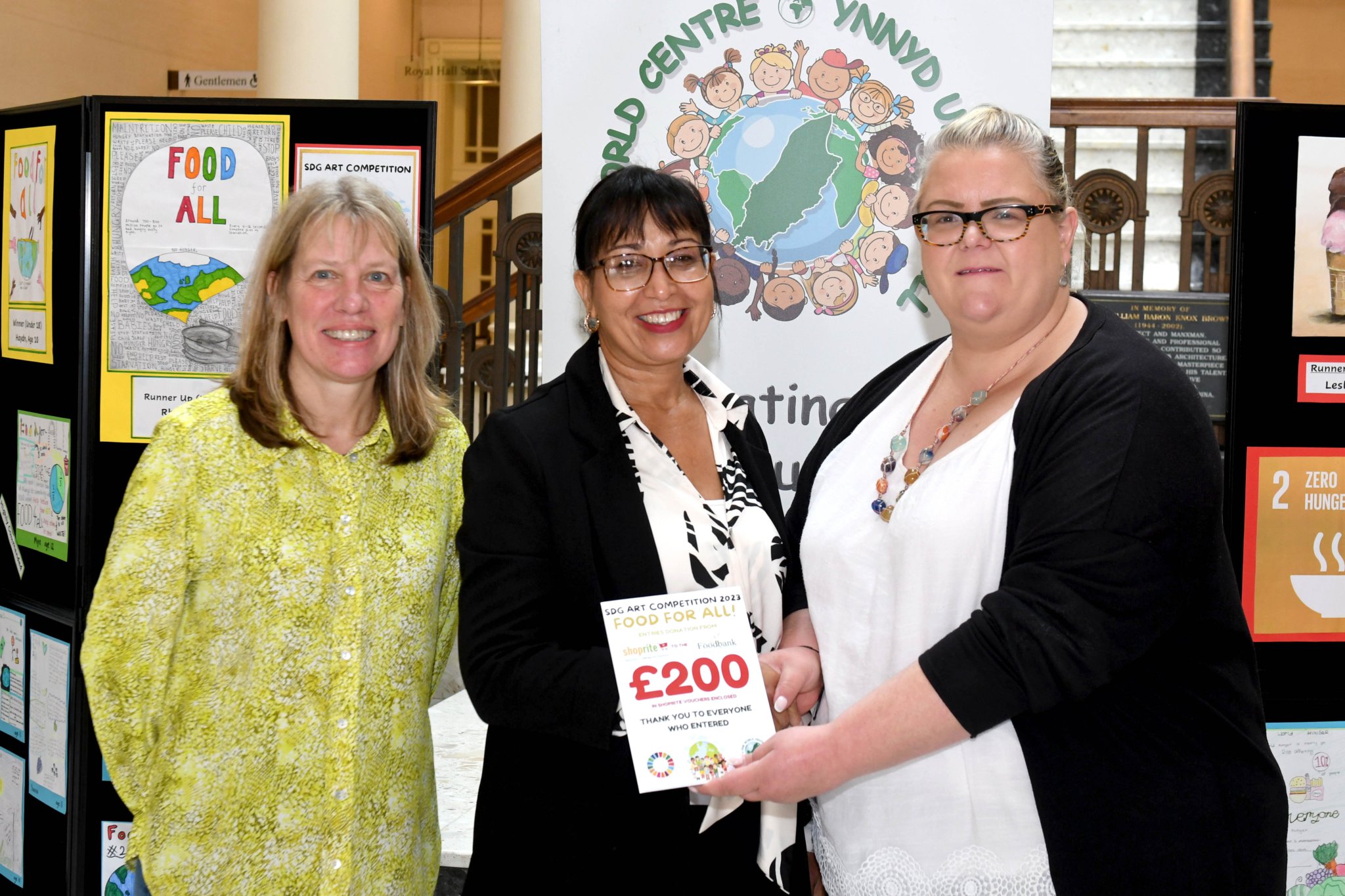 A display of the winning entries from the One World Centre’s ‘Food For All’ art competition, inspired by the UN’s Sustainable Development Goals (SDG) - pictured left to right: Wendy Shimmin (One World Centre), Madina Sharpe (Isle of Man Food Bank) and DEFA Minister Clare Barber